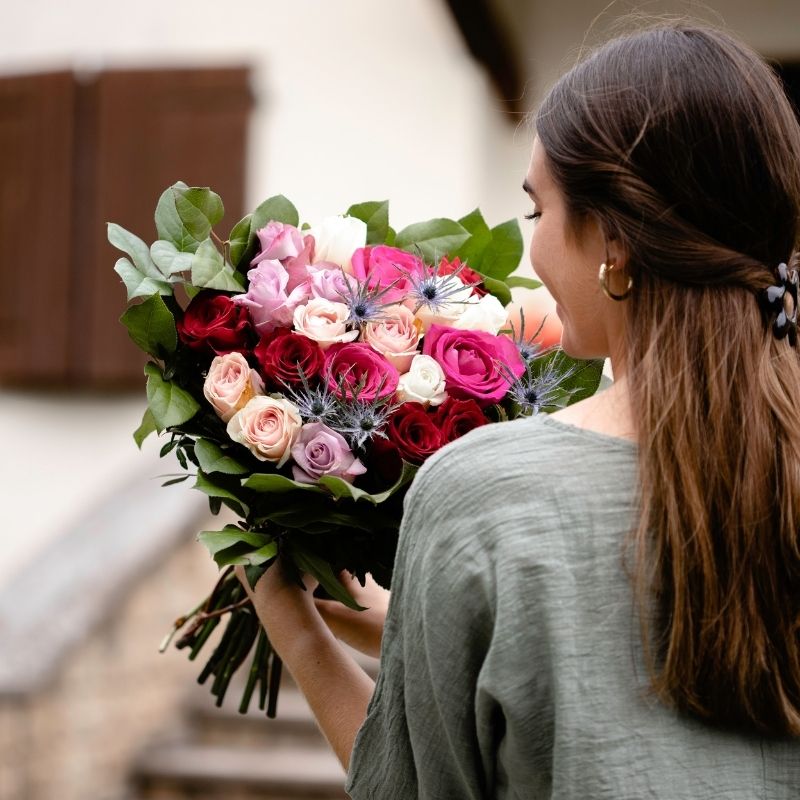 La niña le da a su mamá una caja de regalo y un ramo de flores de